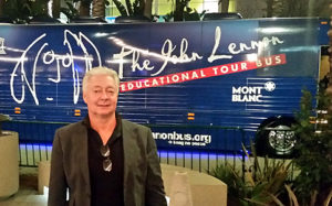 Photo of Alex Ayzin standing in front of John Lennon Educational Bus that travels the United States giving young people a chance to create original music with state of the art instruments and equipment. 