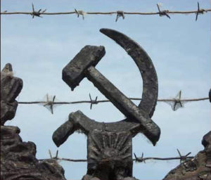 Image of the Hammer and Sickle, the symbol of the Soviet Union, with barbed wire in the foreground that shows what the Iron Curtain meant for millions trapped behind it. 